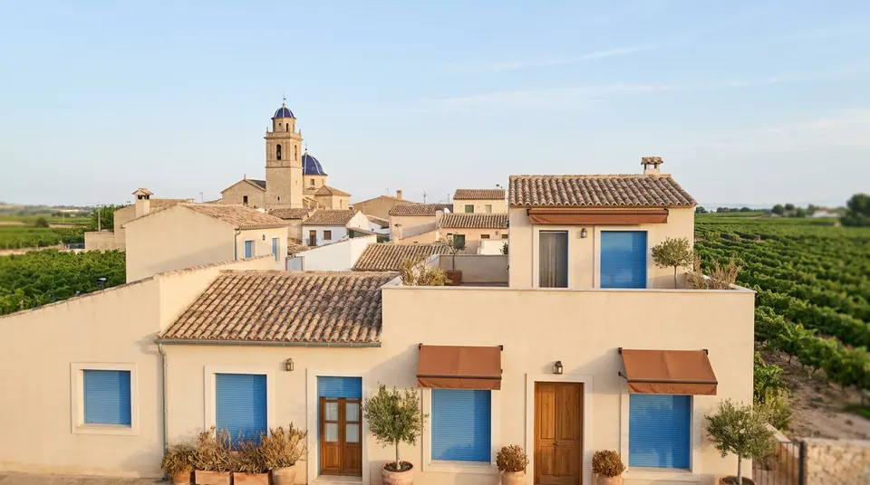 Casas encaladas con persianas y un campanario entre viñedos